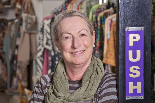Headshot of the owner of The Emporium, homeware and gift shop, leaning against shop door with a relaxed smile.