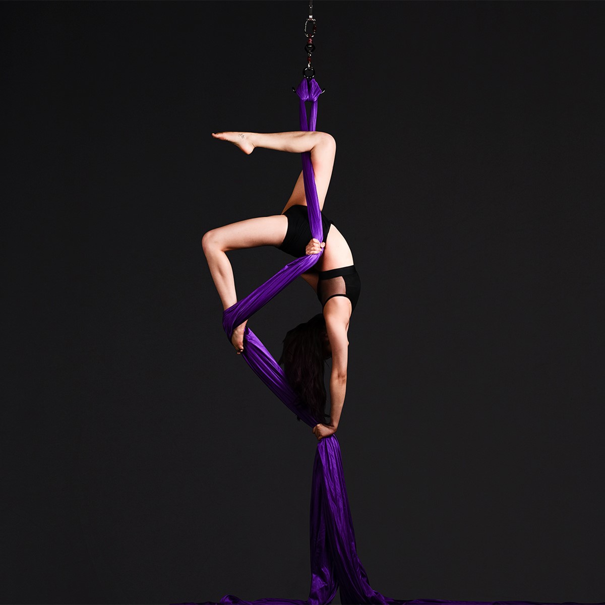 fine-photography-aerial-silks-upside-down-pose-performing-arts Aerial silks performer posing upside down with purple silks
